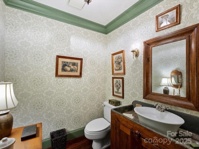 bathroom featuring toilet, crown molding, vanity, wallpapered walls, and wood finished floors