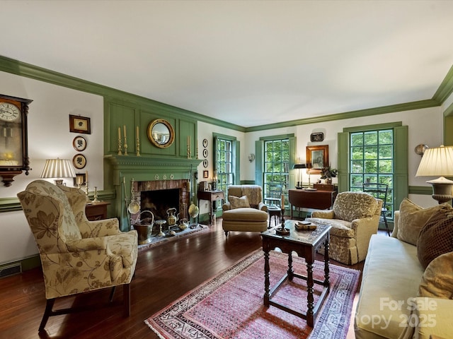 living area featuring ornamental molding, a brick fireplace, and dark wood-style floors