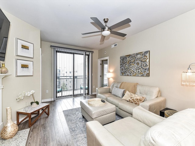 living area with baseboards, a ceiling fan, wood finished floors, and visible vents