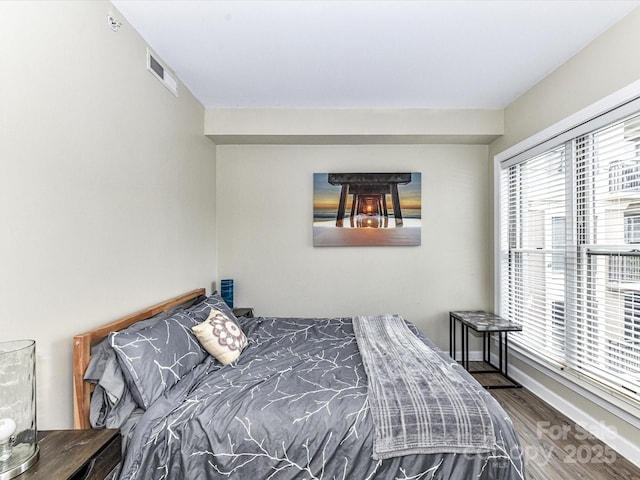 bedroom with baseboards, wood finished floors, and visible vents