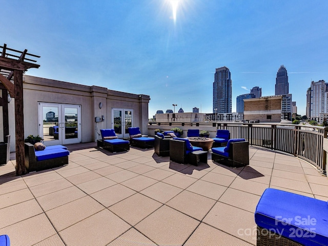 view of patio featuring a view of city, french doors, and an outdoor living space with a fire pit