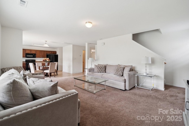 living area with baseboards, light carpet, and visible vents