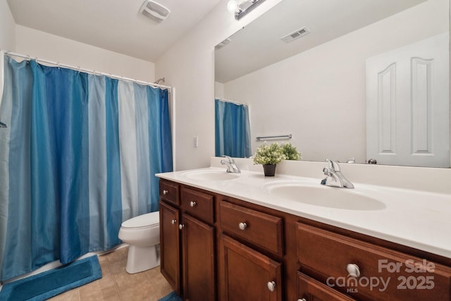 bathroom with a sink, toilet, double vanity, and visible vents