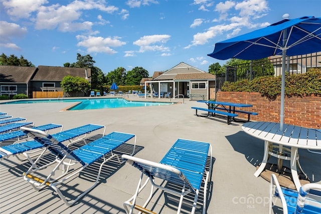 community pool with fence and a patio area