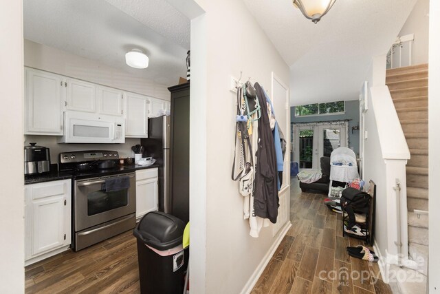 kitchen with stainless steel range with electric cooktop, white microwave, dark wood-type flooring, and white cabinets
