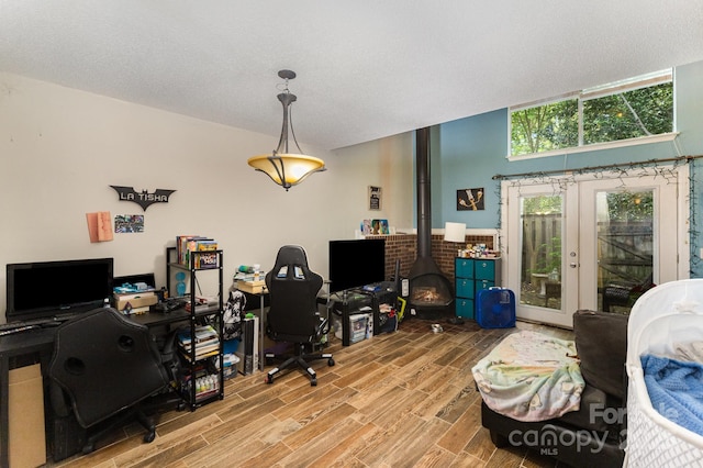 office space featuring wood finished floors, french doors, and a wood stove