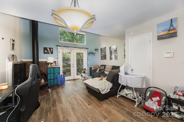 living area with french doors, wood finished floors, a wood stove, and lofted ceiling