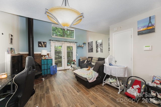 living area featuring french doors, wood finished floors, a wood stove, and vaulted ceiling