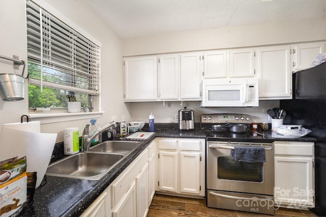 kitchen with white microwave, stainless steel electric range, a sink, white cabinetry, and dark wood-type flooring