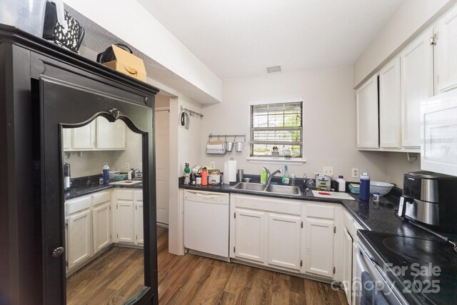 kitchen featuring white appliances, a sink, dark wood finished floors, and dark countertops