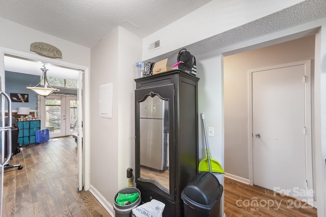 workout room with french doors, wood finished floors, baseboards, and a textured ceiling