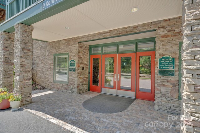 view of exterior entry featuring french doors and stone siding