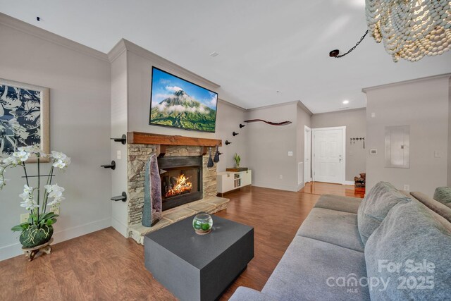 living area with crown molding, baseboards, a fireplace, and wood finished floors