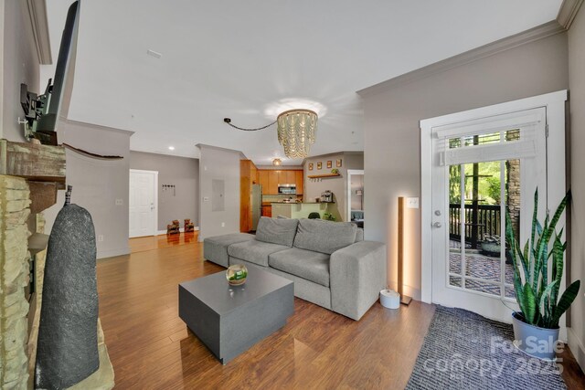 living room with an inviting chandelier, ornamental molding, recessed lighting, and wood finished floors