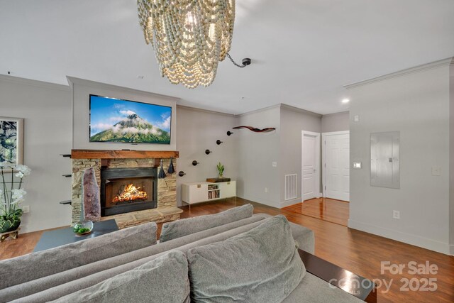 living room featuring visible vents, ornamental molding, wood finished floors, a fireplace, and a notable chandelier