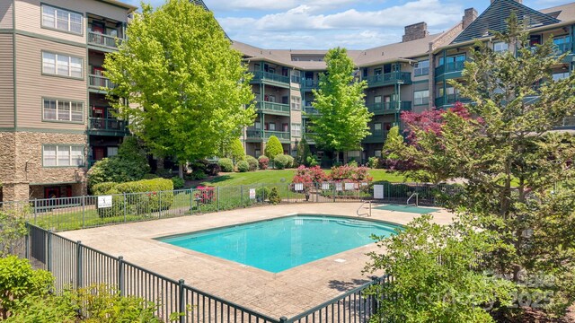 community pool with a patio area and fence
