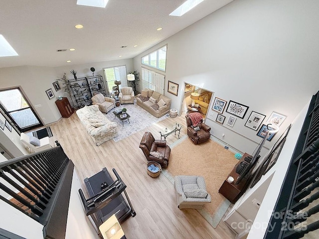 living room featuring a skylight, high vaulted ceiling, recessed lighting, and wood finished floors