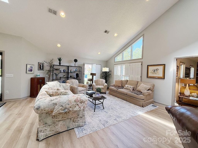 living room with visible vents, recessed lighting, light wood finished floors, and high vaulted ceiling