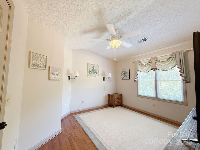 empty room with ceiling fan, light wood-style floors, a textured ceiling, baseboards, and visible vents