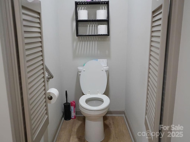 bathroom with baseboards, toilet, and wood finished floors
