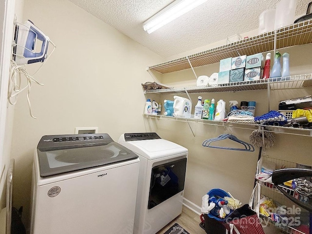 laundry area with laundry area, a textured ceiling, wood finished floors, and washing machine and clothes dryer