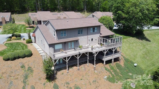 rear view of house featuring a yard, a deck, and roof with shingles