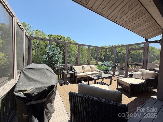 wooden deck with an outdoor living space and area for grilling