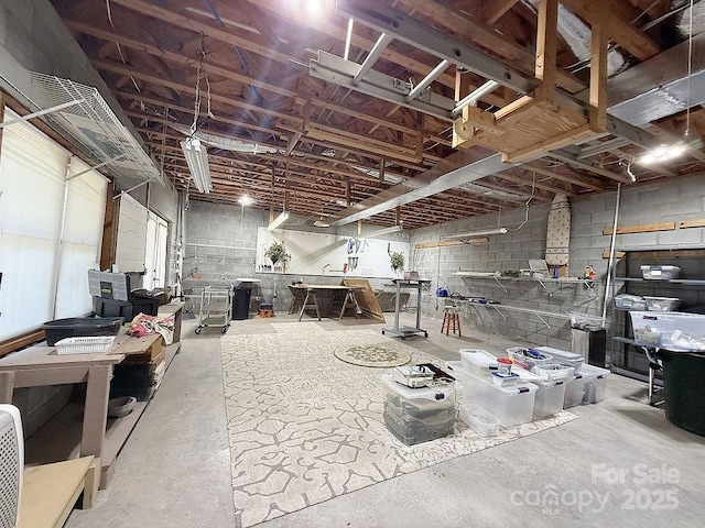 unfinished basement featuring concrete block wall and a workshop area
