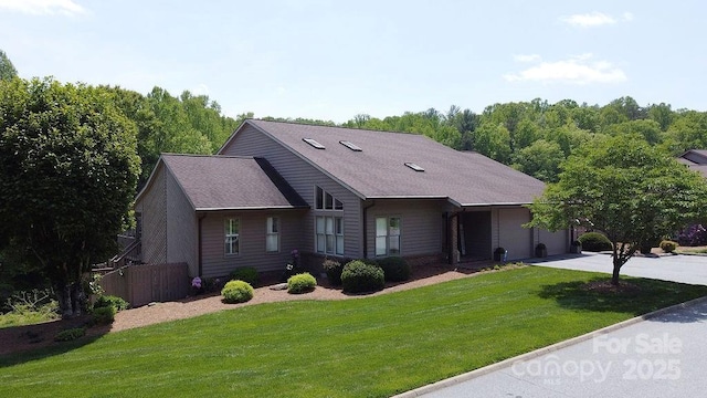 ranch-style house with fence, an attached garage, concrete driveway, and a front lawn