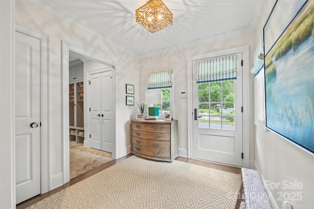 entryway featuring wood finished floors, crown molding, and baseboards