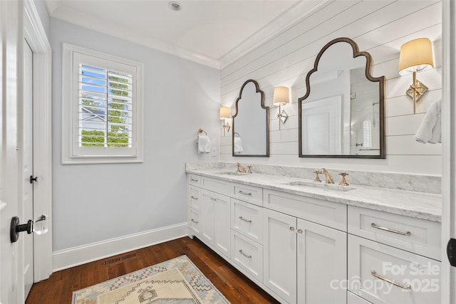 bathroom featuring ornamental molding, double vanity, baseboards, wood finished floors, and a shower