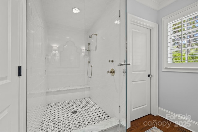 bathroom with a stall shower, wood finished floors, crown molding, and baseboards