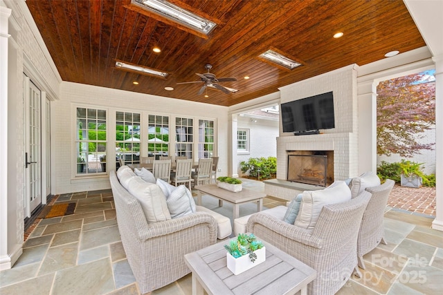 view of patio / terrace with an outdoor living space with a fireplace and a ceiling fan