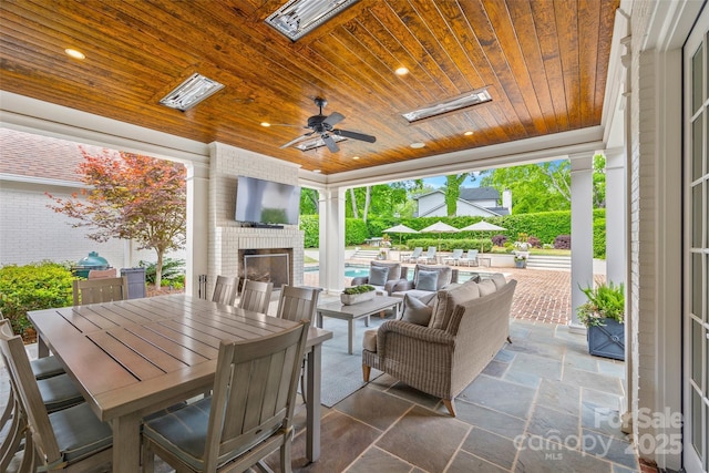 view of patio / terrace with ceiling fan, an outdoor pool, outdoor dining space, and an outdoor brick fireplace