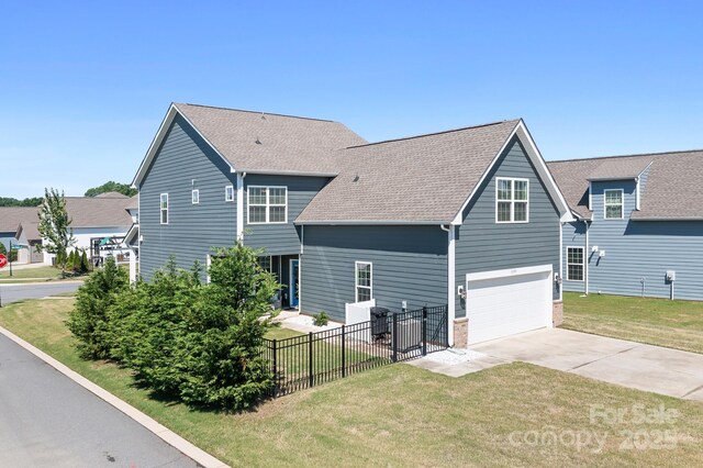 back of house with concrete driveway, an attached garage, and a shingled roof