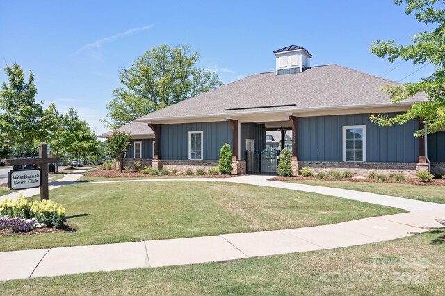 view of front facade featuring a front lawn, a gate, roof with shingles, and board and batten siding
