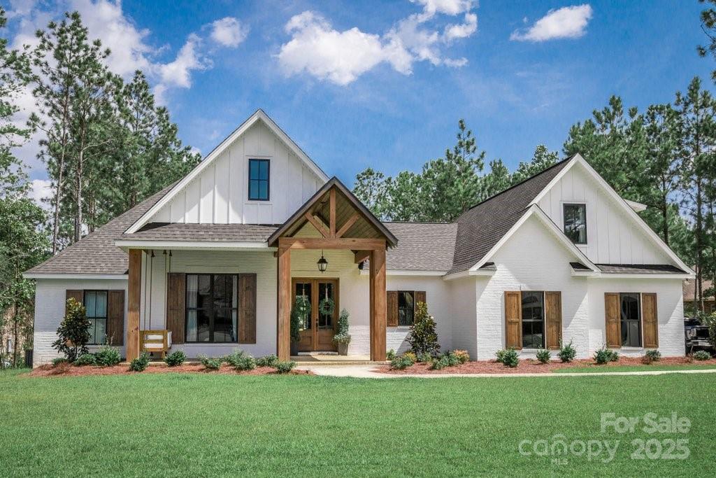 0 Ellis Spring Ct, Albemarle, NC 28001 - modern farmhouse with board and batten siding, french doors, roof with shingles, and a front lawn