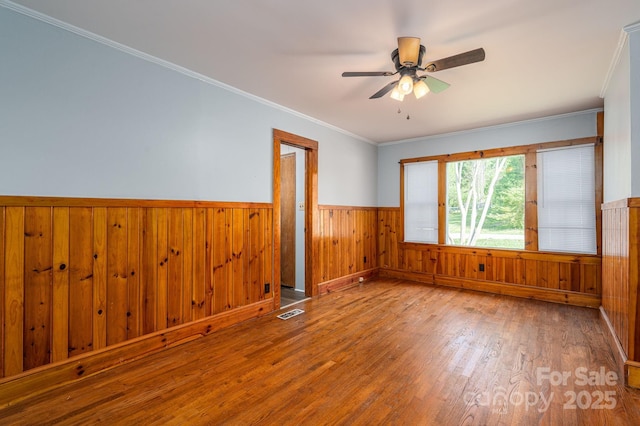 406 Arrowood St SE, Lenoir, NC 28645 - empty room with ceiling fan, visible vents, crown molding, wainscoting, and wood finished floors