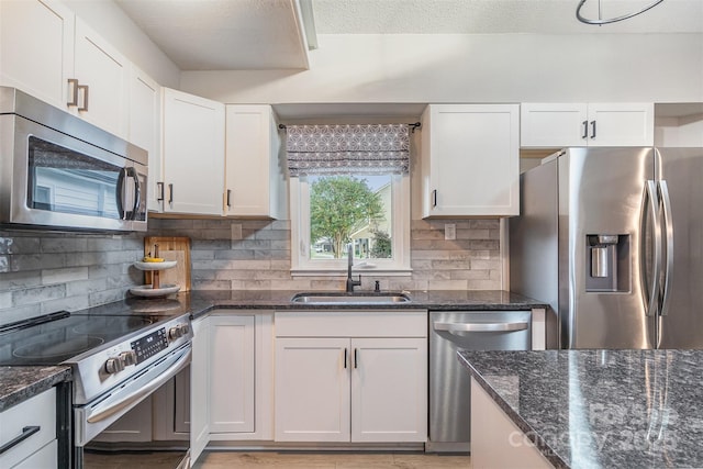 317 Commodore Loop, Mooresville, NC 28117 - kitchen featuring stainless steel appliances, a sink, white cabinetry, tasteful backsplash, and dark stone countertops
