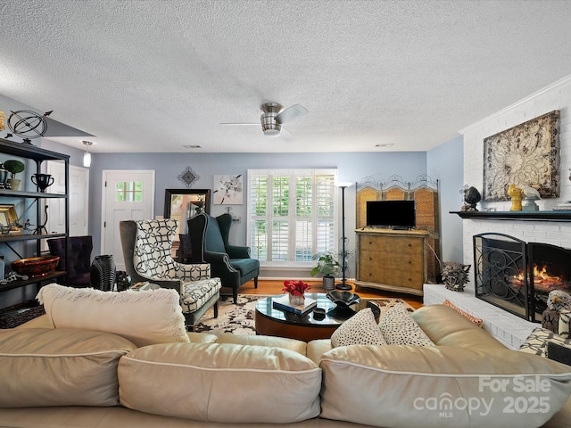 living area with healthy amount of natural light, a textured ceiling, a brick fireplace, and a ceiling fan