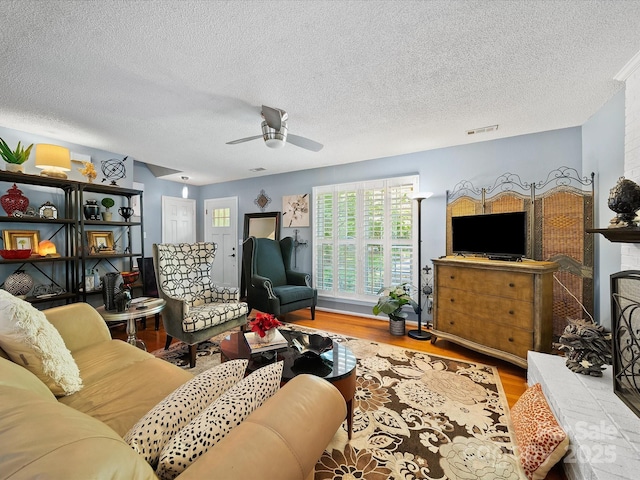 living area featuring wood finished floors, a textured ceiling, and a ceiling fan