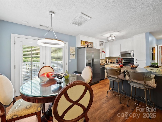 dining room with light wood-type flooring and a textured ceiling