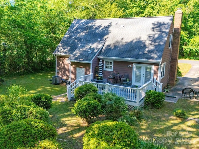 back of property with a chimney, a yard, cooling unit, french doors, and a shingled roof
