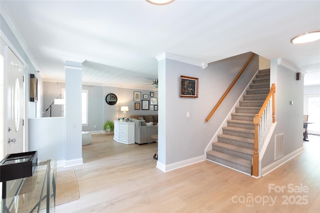 staircase with baseboards, visible vents, ornamental molding, and wood finished floors
