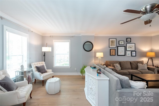 living room with crown molding, a ceiling fan, baseboards, and light wood-style floors