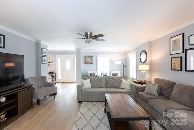 living area featuring light wood-type flooring, ornamental molding, and ceiling fan