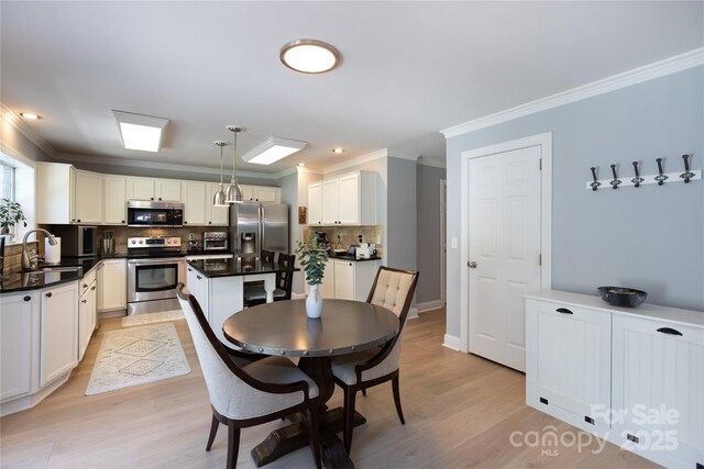 dining space featuring crown molding, baseboards, and light wood-type flooring