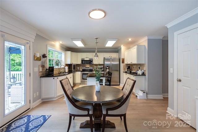 dining area with crown molding, light wood finished floors, and baseboards