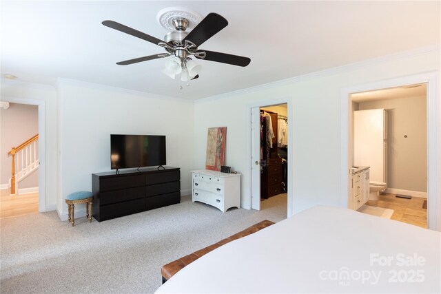 bedroom with a closet, ornamental molding, baseboards, a walk in closet, and ceiling fan