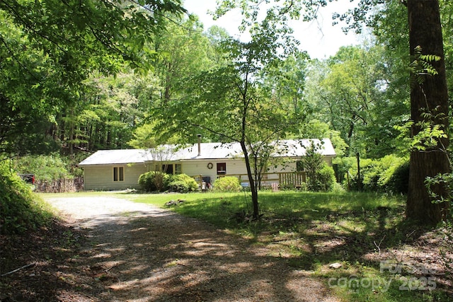single story home featuring driveway and a forest view
